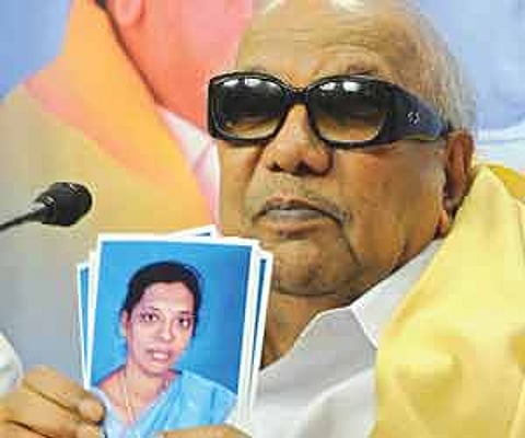 DMK chief M Karunanidhi holds up photos of the party’s bypoll candidate A Latha Adhiyaman.