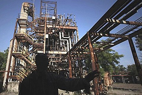 A security guard is silhouetted against defunct machinery at the Union Carbide pesticide plant in Bhopal. AP