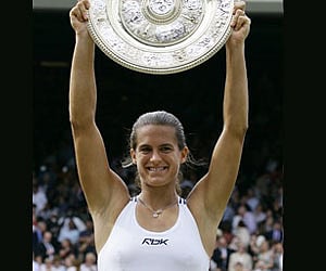 Amelie Mauresmo holds the Championship plate, after defeating Justine Henin in the singles final on the Centre Court at Wimbledon. (AP / File photo)