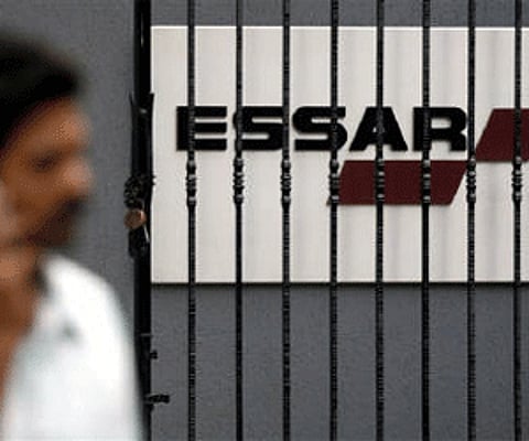 A man speaks on a mobile phone as he walks past an Essar logo in Mumbai in this February 15, 2007 file photo. (Reuters)