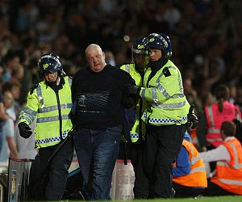 A soccer supporter is led away by British riot police officers during a match between West Ham and Millwall, at Upton Park Stadium. (AP)