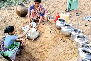 Tribals collecting drinking water from an oozing pit on the banks of Malluru stream in Mangapet.