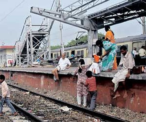 Passengers negotiate the rail track at Vyasarpadi Jiva station; and (inset) the debris of the recent train collision on the platform.