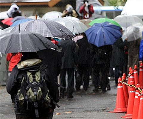 People line up in the rain to participate in a lottery for spectators seats for actress Noriko Sakai's trial in Tokyo. (Photo: AP)