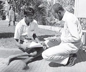 An official helping a physically handicapped person in filling a pension form at Rachabanda in Karimnagar on Saturday.
