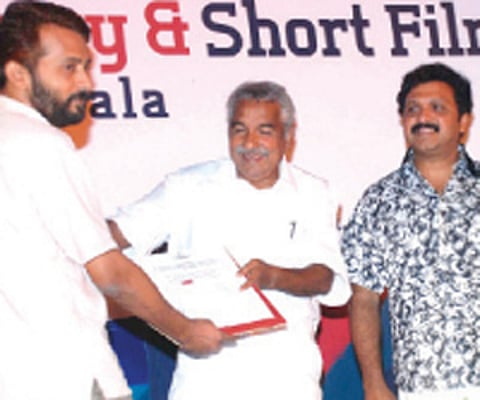 Chief Minister Oommen Chandy presenting the certificate of merit to K R Manoj for the best long documentary ‘A pestering journey’ at the concluding ce