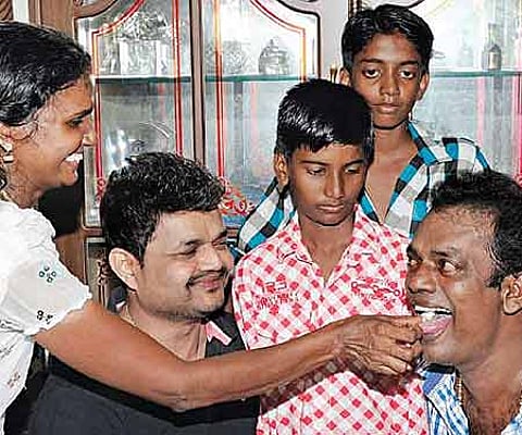 Salim Kumar tasting a piece of cake from wife Sunitha at his residence. Actor Nadirsha and Salim Kumar’s sons Aromal and Chandu look on | Express.
