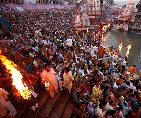 Hindu priests rotate a traditional oil lamp as devotees pray on the banks of the River Ganges during the Kumbh Mela. AP