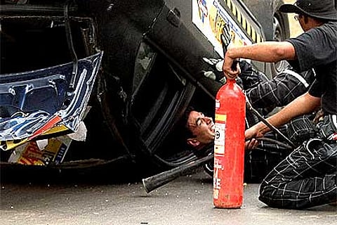 Bollywood actor Akshay Kumar comes out of a car after performing a stunt. PTI