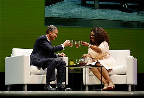 Howard Schultz, left, chairman and CEO of Starbucks Coffee Company, clinks tea cups with Oprah Winfrey, right, to announce their partnership to offer Teavana Oprah Chai tea at Starbucks' annual shareholders meeting in Seattle. (AP Photo/Ted S. Warren)