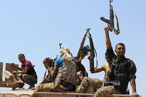 Houthis hold up their weapons as they ride on an armored vehicle near the strait of Bab al-Mandab, west of the southern port city of Aden