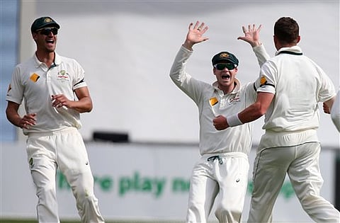 Australia's Peter Siddle, is congratulated by teammates Steve Smith, centre, and Australia's Mitchell Starc, left, after taking the wicket of New Zealand's Ross Taylor during their cricket test in Adelaide.