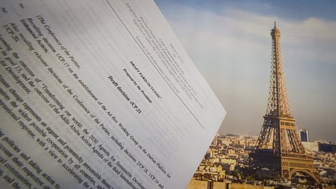 An illustration picture taken on December 10, 2015, in Paris shows a draft for the outcome of the COP21 United Nations conference on climate change next to a picture of the Eiffel Tower.