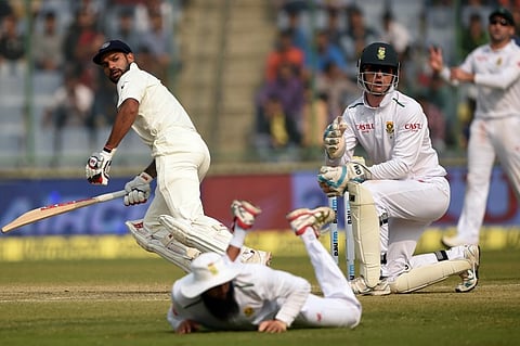 India's Shikhar Dhawan (L) looks back at South Africa's fielders after playing a shot during the third day of the fourth Test cricket match between India and South Africa at the Feroz Shah Kotla stadium in New Delhi. |AFP