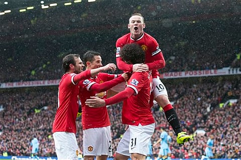 Manchester United's Marouane Fellaini, bottom right, celebrates with teammates including captain Wayne Rooney, top, after scoring during the English Premier League soccer match between Manchester United and Manchester City at Old Trafford Stadium, Manche