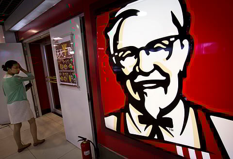 A menu with words "everyday half-price" is placed in front of a KFC fast food restaurant in Beijing, China | AP