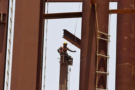 A labourer sits atop a steel girder at the construction site of a hospital building in Ahmedabad | REUTERS