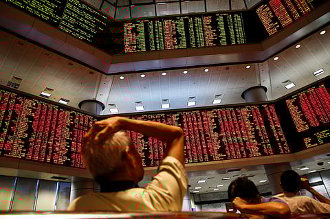 People watch trading boards at a private stock market gallery in Kuala Lumpur, Malaysia