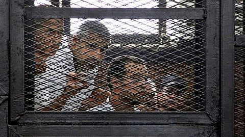 In this Monday, June 23, 2014, file photo, from left, Australian correspondent Peter Greste, Canadian-Egyptian acting bureau chief of Al-Jazeera Mohamed Fahmy, and Egyptian producer Baher Mohammed, appear in a defendant's cage in a courtroom in Cairo, E
