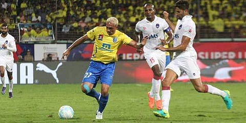Kerala Blasters FC’s Michael Chopra vies with Delhi Dynamos FC players during the ISL encounter in Kochi on Sunday. Chopra, who had the best opportunity to score just seconds before the first half end
