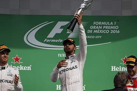 Mercedes driver Lewis Hamilton, center, holds the trophy aloft as he celebrates on the podium his victory in the Formula One Mexico Grand Prix auto race at the Hermanos Rodriguez in Mexico.(Photo|AP)
