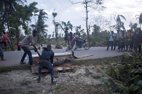 Residents try to put the body of victim of Hurricane Matthew in a coffin. (Photo | AP)