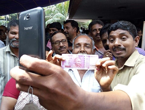 People take selfies with the new currency in Kozhikode. ( Sanesh A. | EPS)