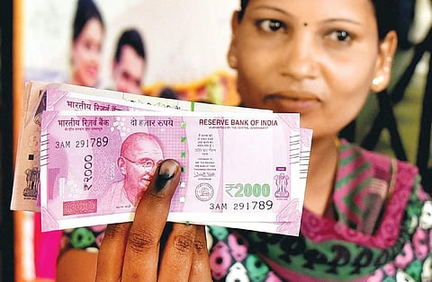 A woman displays the new currency notes and the indelible ink after exchanging cash at a bank in Bengaluru on Wednesday. (File photo |EPS)