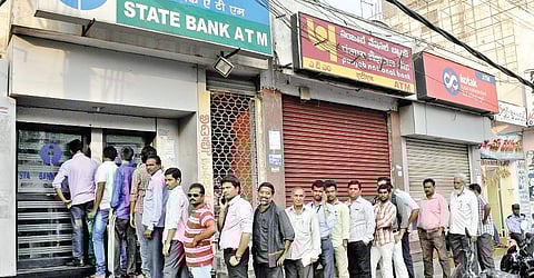 People withdraw money from an SBI ATM, even as the ATMs of private banks remain closed at Labbipet; (right) Out of service board hangs to the door of an ICICI ATM in Vijayawada on Friday | P RAVINDRA