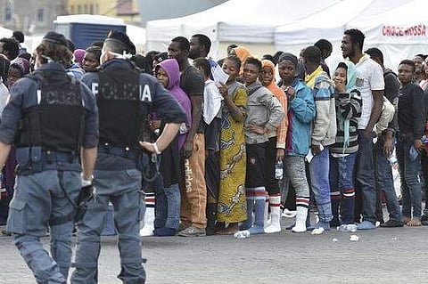 In this file photo, Police monitor rescued migrants standing in a line after they were disembarked from a ship in Italy. (AP)