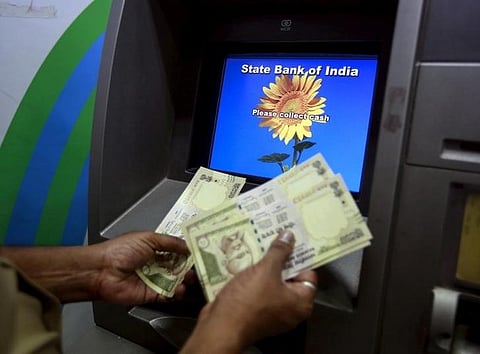 A man counts money after withdrawing it from a State Bank of India automated teller machine (ATM) in Mumbai. (File photo | Reuters)