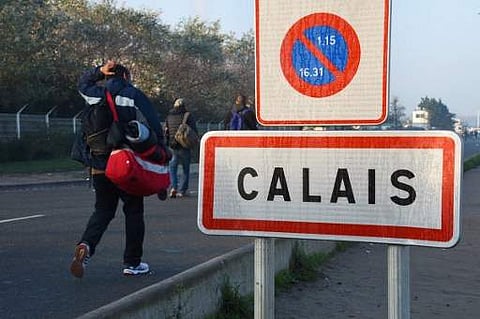 Migrants walk past a Calais city limit sign. (File photo | AFP)