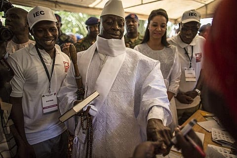 Incumbent Gambian president Yahya Jammeh (C) has his finger inked before casting his marble in a polling station. (Photo | AFP)