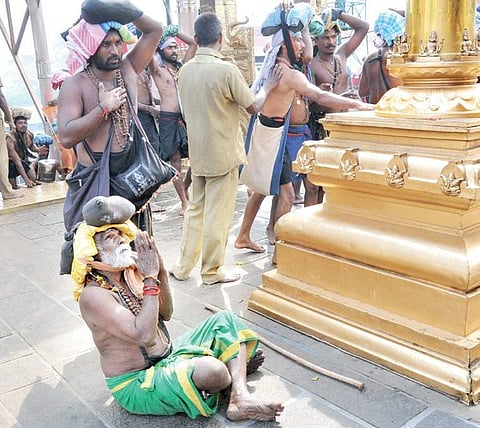 An elderly pilgrim offering worship in front of the golden flagmast of Sabarimala Lord Ayyappa temple on Wednesday| SHAJI VETTIPURAM
