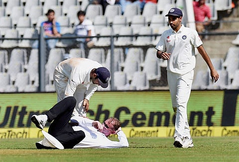 India's Cheteshwar Pujara helps the Umpire Paul Reiffel after he fell down during the first day of the fourth Test match between India and England in Mumbai on Thursday. | PTI
