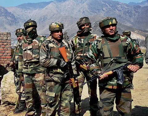 Panpore ecurity forces personnel looks at the JKEDI building where militants were holed up during an encounter at Sampora in Pampore on Monday. | PTI