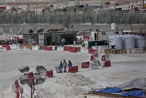 Foreign workers walk between safety barricades at the site of the pitch of the Al-Wakra Stadium when it was under construction for the 2022 World Cup in Doha, Qatar.