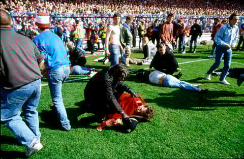 FILE - In this April 15, 1989 file photo police, stewards and supporters tend and care for wounded supporters on the field at Hillsborough Stadium, in Sheffield, England. The 96 Liverpool soccer fans who died in the Hillsborough Stadium disaster were “unl
