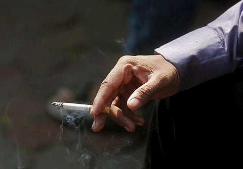 A man smokes a cigarette along a road in Mumbai,