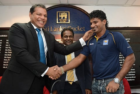 Sri Lankan cricketer Kusal Perera (R) shakes hands with Sports Minister Dayasiri Jayasekara (L) as Sri Lankan Cricket President Thilanga Sumathipala looks on during a press conference in Colombo on May 12, 2016. |AFP