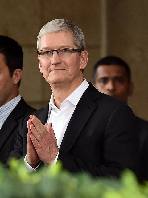 Apple chief executive Tim Cook greets onlookers as he leaves the Taj Mahal Palace hotel in Mumbai on May 18, 2016. | AFP