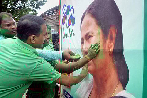 Trinamool Congress supporters smear color on a poster of party chief Mamata Banerjee as they celebrate their win in West Bengal assembly elections in Tripura's Agartala on Thursday. | PTI