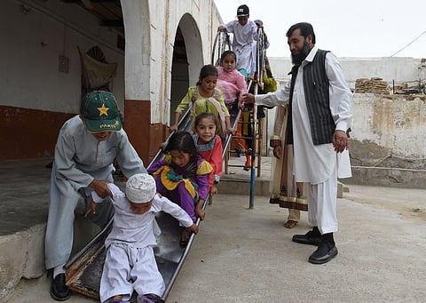 Pakistani father Sardar Haji Jan Mohammad Khilji plays with some of his children at his residence in Quetta | AFP