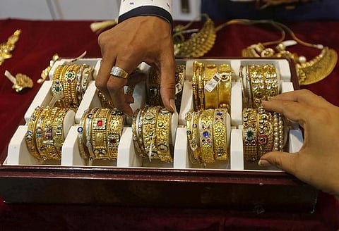 A salesman helps a customer to select gold bangles at a jewelry showroom in Mumbai. (File | Reuters)