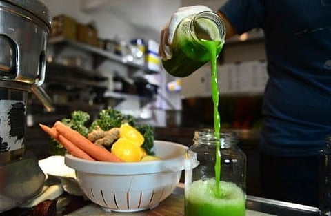 Alexander Mendez displays the juice of the "Green Giant", which contains cucumber lemon, celery, spinach and kale, at the Silver Lake Juice Bar | AFP