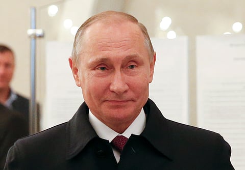 Russian President Vladimir Putin smiles at a polling station during a parliamentary election in Moscow, Russia. | AP