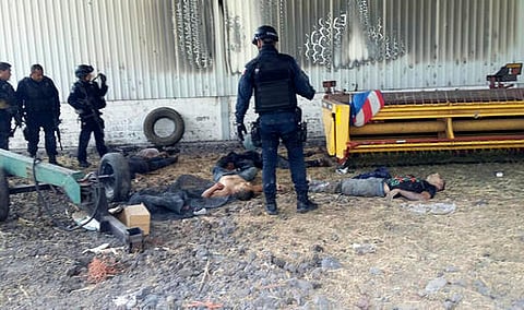 Federal police stand near the bodies of men who authorities say were suspected cartel gunmen at the Rancho del Sol, near Ecuanduero, in western Mexico. (AP)