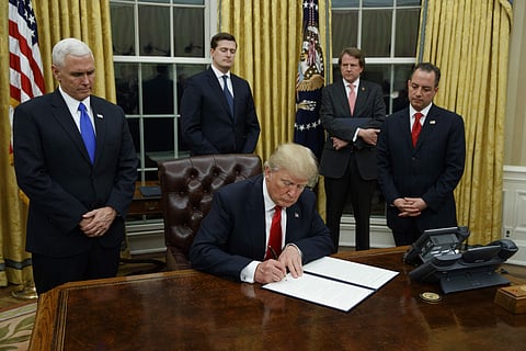 President Donald Trump, flanked by Vice President Mike Pence and Chief of Staff Reince Priebus, signs his first executive order on health care.(Photo | AP)