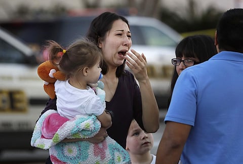 A woman holds her child after San Antonio police helped her and other shoppers exit the Rolling Oaks Mall, Sunday, Jan. 22, 2017, in San Antonio, after a deadly shooting. | AP