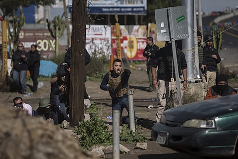 Mexican police take cover with guns drawn and pointed towards protesters who were blocking a fuel facility in Rosarito, near Tijuana, Mexico, Saturday, Jan. 7, 2017. | AP